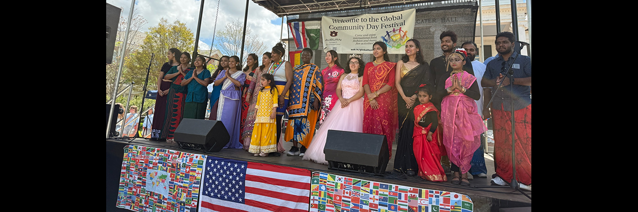Group of people standing on stage dressed in cultural attire.