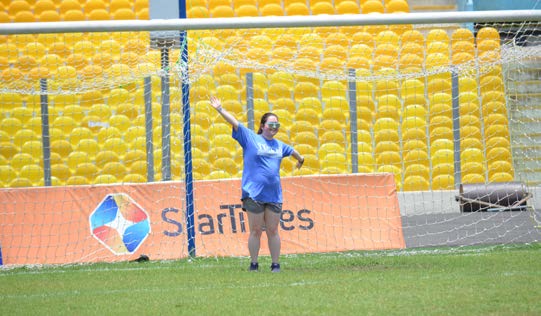 Girl in blue shirt stand in front of soccer goal