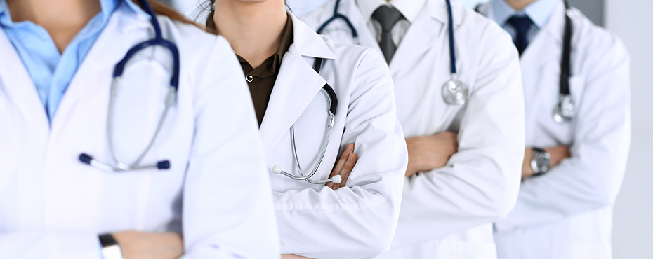 Doctors in white coats standing in a line with arms crossed