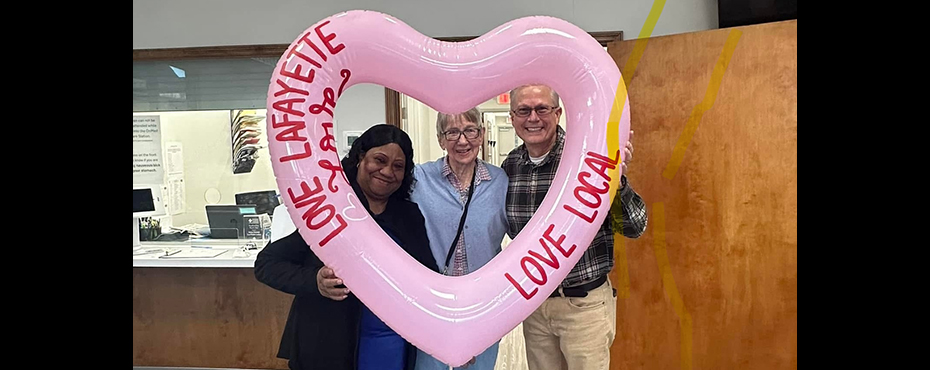 Chambers community health worker and volunteers holding up a pink inflatable that says 'Love LaFayette Love Local.'